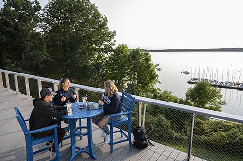 Students sit around a table overlooking Mount Hope Bay