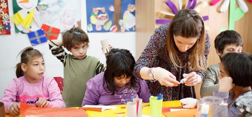 Young students work on craft projects with a female teacher